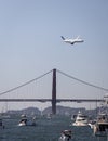 United Airlines Boeing 777 jet flying over the Golden Gate Bridge in San Francisco with boats Royalty Free Stock Photo