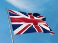 United Kingdom flag on a pole waving. United Kingdom of Great Britain and Northern Ireland realistic flag waving against blu sky.