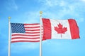 United States and Canada two flags on flagpoles and blue cloudy sky