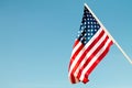 United States flag blows in the wind against a blue sky attached to the wall from the side.