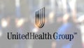 UnitedHealth Group logo on a glass against blurred crowd on the steet. Editorial 3D rendering Royalty Free Stock Photo