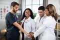 Unity and teamwork concept where four doctors and nurses in a medical team stacking hands together