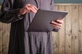 A universal large-format gray tablet in female hands in a harmonious gray cotton dress