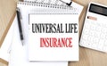 UNIVERSAL LIFE INSURANCE is written in white notepad near a calculator, clipboard and pen. Business concept Royalty Free Stock Photo