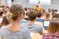Academic lecture at university classroom with students seated at desks, instructor presenting at front, projector screen Royalty Free Stock Photo