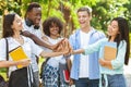 University Friendship. Portrait Of Joyful International Students Joining Hands Outdoors