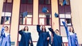 University graduates  throwing graduation hats in the air. Group of happy graduates in academic dresses near university building Royalty Free Stock Photo