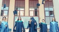 University graduates  throwing graduation hats in the air. Group of happy graduates in academic dresses near university building Royalty Free Stock Photo