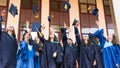 University graduates  throwing graduation hats in the air. Group of happy graduates in academic dresses near university building Royalty Free Stock Photo