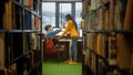 University Library: Boy Uses Personal Computer at His Desk, Talks with Girl Classmate Give High Fi Royalty Free Stock Photo