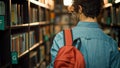 University Library: Student Walks Between Rows of Bookshelves Searching for Right Book Title for C Royalty Free Stock Photo