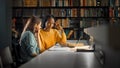 University Library: Two Gifted Girl Students Study, Use Laptop Computer, Help Each Other with Advi