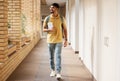 University student, college and indian man walking with a smile and backpack down campus corridor. Gen z male happy Royalty Free Stock Photo