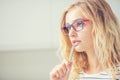 University student girl pensive with pen on her lips. Portrait of thinking woman with glasses Royalty Free Stock Photo