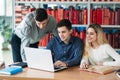 University students sitting together at table with books and laptop. Happy young people doing group study in library Royalty Free Stock Photo