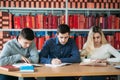 University students sitting together at table with books and laptop. Happy young people doing group study in library Royalty Free Stock Photo