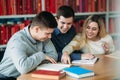 University students sitting together at the table with books and laptop. Happy young people doing group study in library Royalty Free Stock Photo
