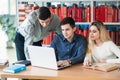 University students sitting together at table with books and laptop. Happy young people doing group study in library Royalty Free Stock Photo