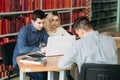 University students sitting together at table with books and laptop. Happy young people doing group study in library Royalty Free Stock Photo