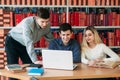 University students sitting together at table with books and laptop. Happy young people doing group study in library Royalty Free Stock Photo