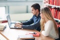 University students sitting together at table with books and laptop. Happy young people doing group study in library Royalty Free Stock Photo