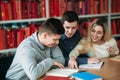 University students sitting together at table with books and laptop. Happy young people doing group study in library Royalty Free Stock Photo