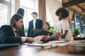 University students sitting together at table with documents and laptop. Happy young people doing group study in college Royalty Free Stock Photo