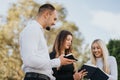 University students study together outside: discussing subjects, exchanging knowledge, teamwork, and helping each other.