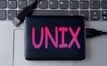 UNIX - acronym on an external drive in gray letters on the background of a laptop