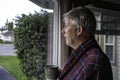 Unkept older man with bed head in housecoat looking out window