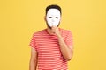 Unknown anonymous man in striped red t-shirt covering his face with white mask, hiding personality, conspiracy and privacy,