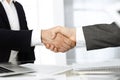 Unknown diverse business people are shaking hands finishing up meeting at the desk in office, close-up. Handshake