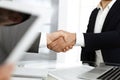 Unknown diverse business people are shaking hands finishing up meeting at the desk in office, close-up. Handshake