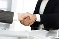 Unknown diverse business people are shaking hands finishing up meeting at the desk in office, close-up. Handshake