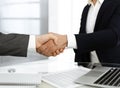 Unknown diverse business people are shaking hands finishing up meeting at the desk in office, close-up. Handshake