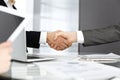 Unknown diverse business people are shaking hands finishing up meeting at the desk in office, close-up. Handshake