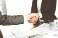 Unknown diverse business people are shaking hands finishing up meeting at the desk in office, close-up. Handshake