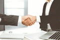 Unknown diverse business people are shaking hands finishing up meeting at the desk in office, close-up. Handshake