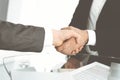 Unknown diverse business people are shaking hands finishing up meeting at the desk in office, close-up. Handshake