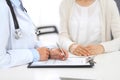 Unknown doctor and female patient discussing something while standing near reception desk in emergency hospit