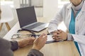 Unknown doctor and patient talk during medical consultation while sitting at table in office. Royalty Free Stock Photo