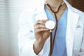 Unknown doctor woman holds stethoscope head, close-up. Physician ready to examine and help patient. Helping and