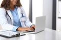 Unknown doctor woman typing on laptop computer while sitting at the desk in hospital office. close-up of hands