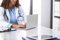 Unknown doctor woman typing on laptop computer while sitting at the desk in hospital office. close-up of hands