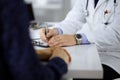 Unknown doctor is writing a receipt for his patient, sitting in his cabinet at hospital office. Physician using Royalty Free Stock Photo