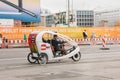 Berlin, October 1, 2017: Unknown elderly bike taxi driver carries passenger on road past people and advertising banners