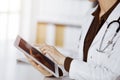 Unknown female doctor using tablet computer in sunny clinic. Perfect medical service in hospital