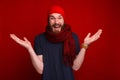 Unknown gesture of bearded guy, in red scarf and hat, standing o Royalty Free Stock Photo