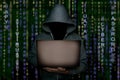 Unknown hacker in the hood with a laptop in his hand on a background of binary code
