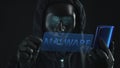 Hacker wearing black mask pulls MALWARE tab from a smartphone. Hacking concept
